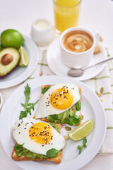 healthy breakfast or snack - sliced avocado and fried egg on toasted bread and cup of coffee