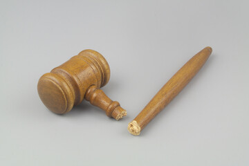 Broken wooden judge gavel on gray background. Concept of iniquity, injustice and lawlessness.