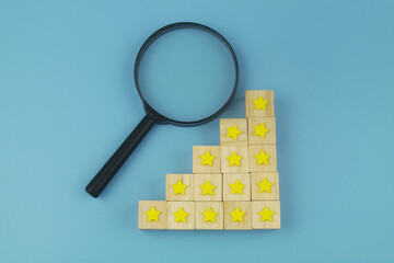 Magnifying glass and wooden cubes with stars. Check rating concept.