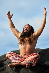 rasta boy with beard doing yoga posture by the sea