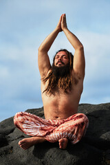 vertical photo. Rasta boy with beard doing yoga posture sitting with his hands together on his...