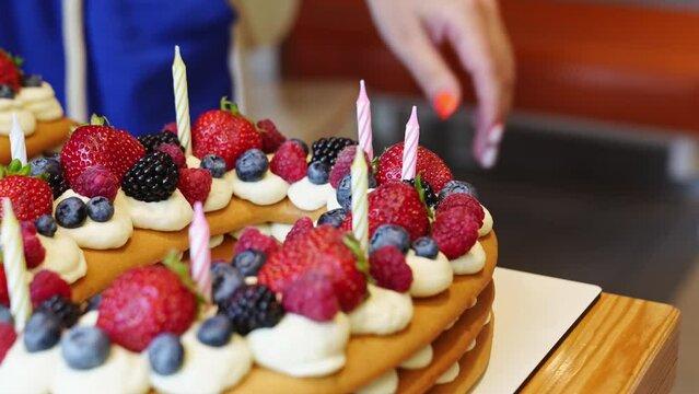 candles put on the cake with berries in the form of the number ten.
