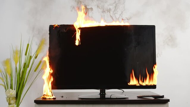 Broken TV screen with smoke and fire in room.