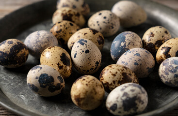 Many quail eggs placed against a wooden background.