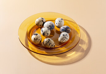 Quail eggs in a glass dish placed on a beige background.