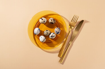 Quail eggs in a glass dish placed on a beige background.