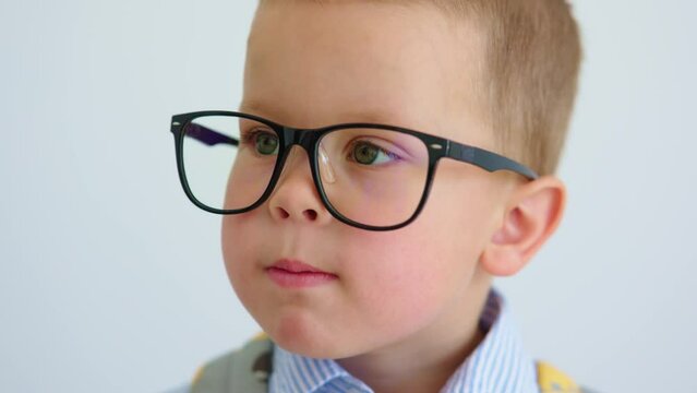 portrait of funny serious baby child boy in glasses making face grimacing on camera. caucasian kid face showing funny faces, blowing lips, smiling and getting shy. emotions wriggling, mugging baby boy