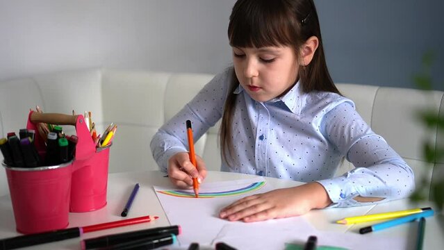 Kids creativity. Child little girl drawing rainbow with colored pencils on paper at home