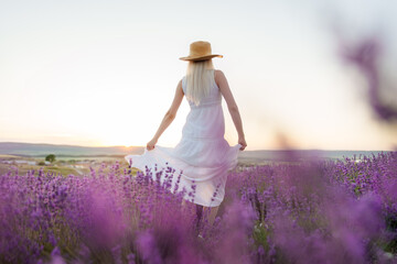 Back view of female in dress and hat standing in lavender field