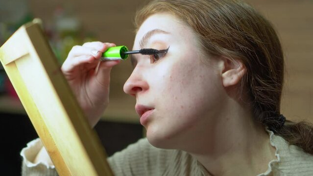 Young woman applying makeup alone.