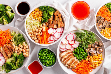 Plates with vegan buddha bowl and chicken buddha bowl with sauces on table, top view