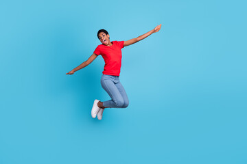 Fototapeta na wymiar Photo of funky cheerful short hair person dressed red t-shirt jumping high arms sides isolated blue color background