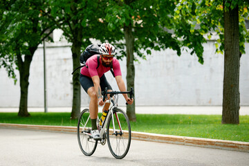 Caucasian handsome young man in protective helmet goes out for bicycle ride through city streets on blurred background. Cyclist male ride bike outdoors in urban.