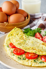 Fototapeta na wymiar Omelet with dill sprinkled with pepper and filled tomatoes