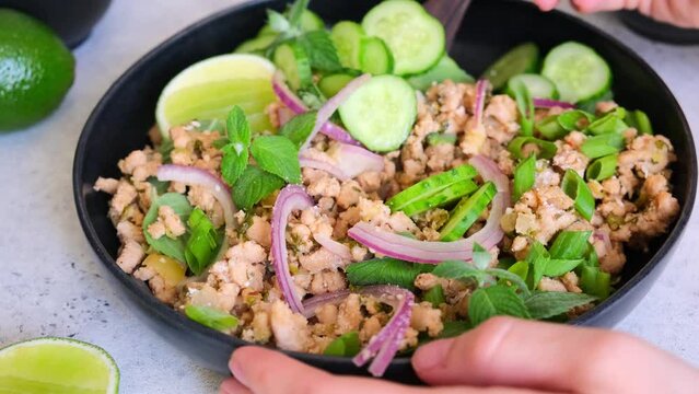 Thai chicken salad larb gai with onion, cucumber and mint. Asian food concept.