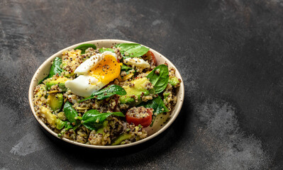 Quinoa buddha bowl with avocado, egg, tomatoes, spinach and sunflower seeds on a dark background. Homemade food. Healthy, clean eating. Vegan or gluten free diet, place for text, top view