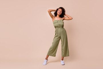 Full length photo of lovely young lady overjoyed soft curly hair product promo wear trendy khaki outfit isolated on beige color background