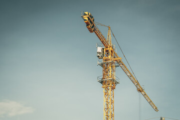 Naklejka premium Tower Crane lattice boom hook clear blue sky sun background. Construction site work building installation