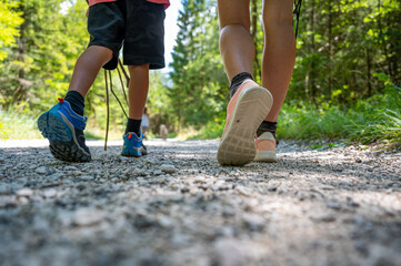 Mother and child walking and hiking on a footpath in green summer forest