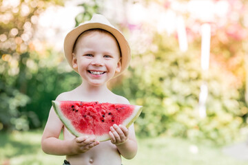 A little boy eats watermelon in the hot summer. Funny happy child with a watermelon in his hands...