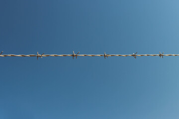 barbed wire against the blue sky, a beautiful landscape there is a place for an inscription