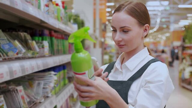 Red-haired woman chooses freshener for flat premise in household goods department. Young lady scans qr-code by phone and takes product in mall closeup