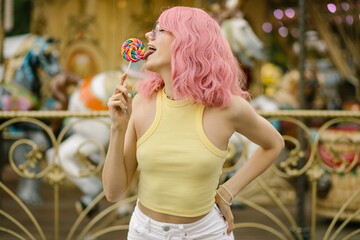 Charming girl playing with two colorful lollipops. Girl with pink hair posing with candies....