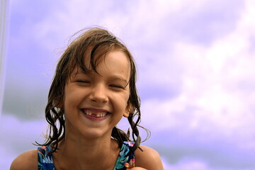 kid cute girl 7 years old wide smile eyes closed no front tooth sky summer beach happy pleasure after swimming from the ground