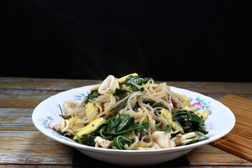 Fried rice noodle mixed with fresh vegetable, peeled shrimp and sliced cuttlefish serving on the plate. Famous hot and spicy seafood menu in Asia restaurant.