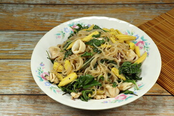 Fried rice noodle mixed with fresh vegetable, peeled shrimp and sliced cuttlefish serving on the plate. Famous hot and spicy seafood menu in Asia restaurant.