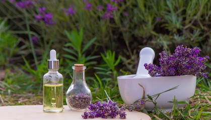 Lavender Essential oil bottle on wood table and flowers field background