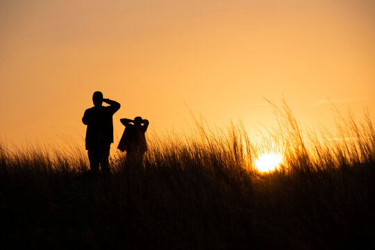 Silhouettes, a young couple is photographed at sunset in the tall grass