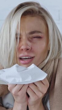 vertical video of sick young woman sneezing in tissue at home