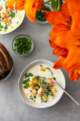 Norwegian salmon red fish soup with vegetables, herbs and cream, top view on the dining table