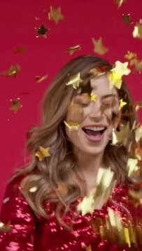 vertical video of cheerful woman throwing confetti on red background