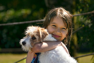 child portrait kid face smile outdoors  holding dog holding white puppy jack russell cute summer sky wet hair after swimming