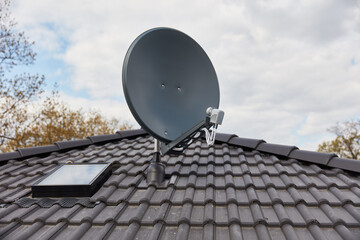Satellite dish on roof of house next to skylight
