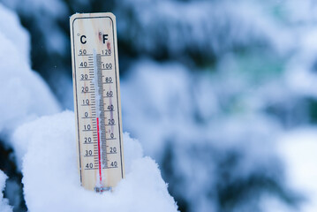 Winter time. thermometer on snow shows low temperatures in celsius or fahreneheit.