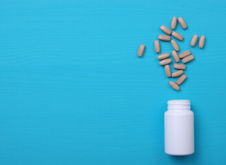 Pills and white bottle on blue background.
