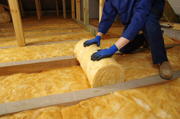 Man installing thermal insulation layer under the roof