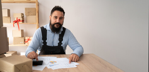 Young Indian man entrepreneur small business SME freelance using the calculator to account for receive order client and check the bill on purchase order preparing package product parcel for shipment.