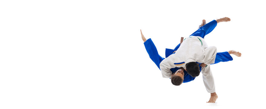 Studio shot of two men, professional judo athletes training isolated over white background. Flyer image