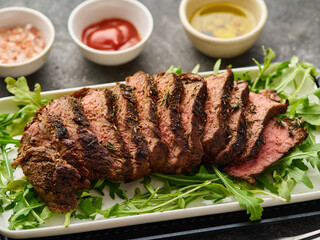Beef tenderloin steak. Grilled sliced beef steak on white plate over grey table. Filet Mignon recipe