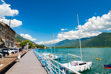 The beautiful promenade of Lovere, on the turquoise waters of Lake Iseo, Italy. Small yacths on the right. Italian alps with white clouds on the background.