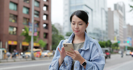 Naklejka premium Woman walk in the street with look at the cellphone