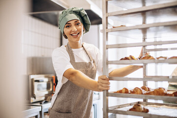 Female baker at the kitchen with croissants