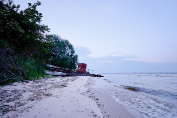 An old shipwreck boat abandoned stand on river sand beach.
