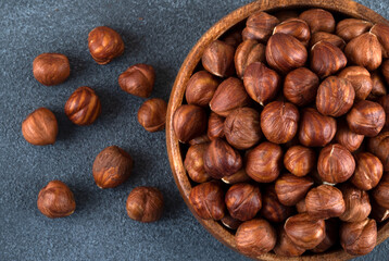 Top view of a bowl full of hazelnuts on dark background