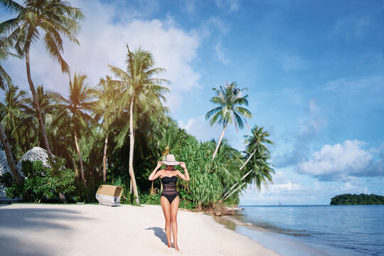 Vacation on the seashore.Young woman walking on the beautiful tropical white sand beach resort.