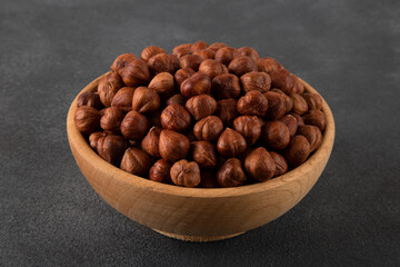 Top view of a bowl full of hazelnuts  on dark background